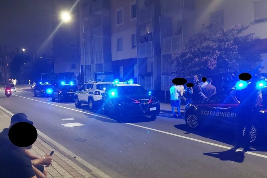 Persone in strada e pattuglie dei carabinieri a Rozzano durante le serate di tensione