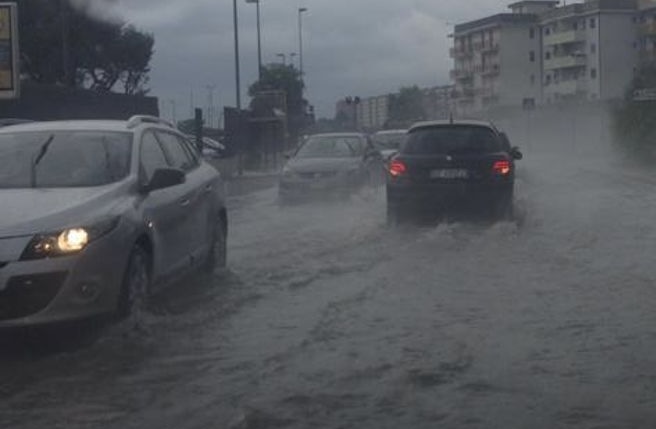Un treno regionale con il mare in burrasca sullo sfondo: in Calabria allerta arancione, treni sospesi tra Lamezia e Rosarno e scuole chiuse
