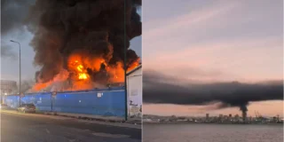 Colonne di fumo nero si levano da un capannone industriale in fiamme in via Brin, a Napoli, dove sono al lavoro i vigili del fuoco